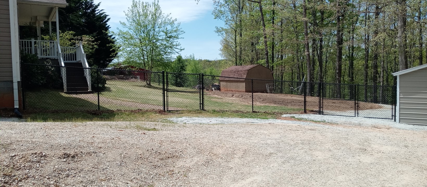 Black chain link fence with a walk gate and a double gate beside a house
