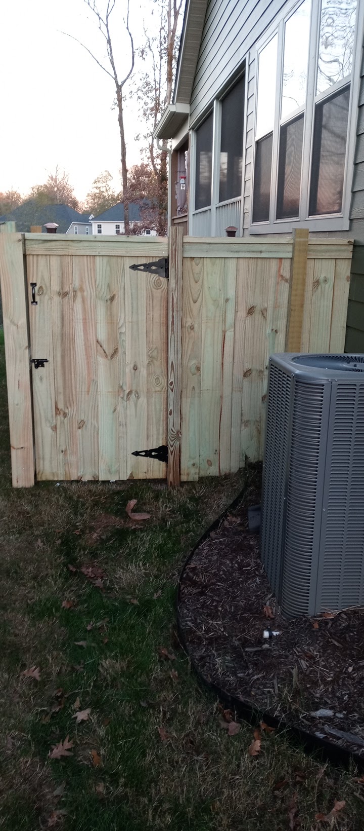 Wood privacy fence with a latched gate beside a house