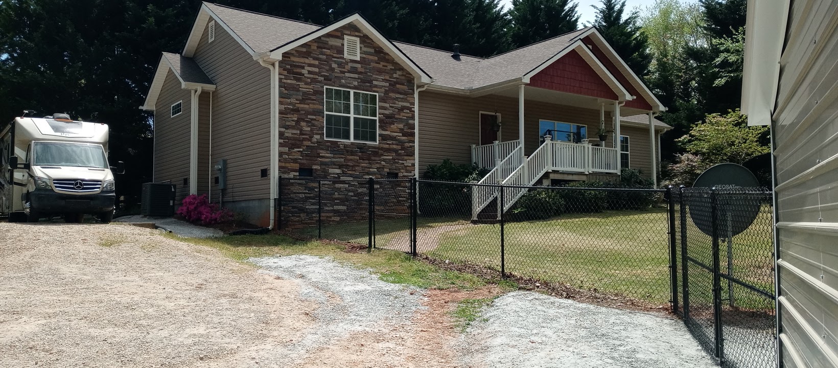 Black chain link fence across the front yard of a stone-and-siding home