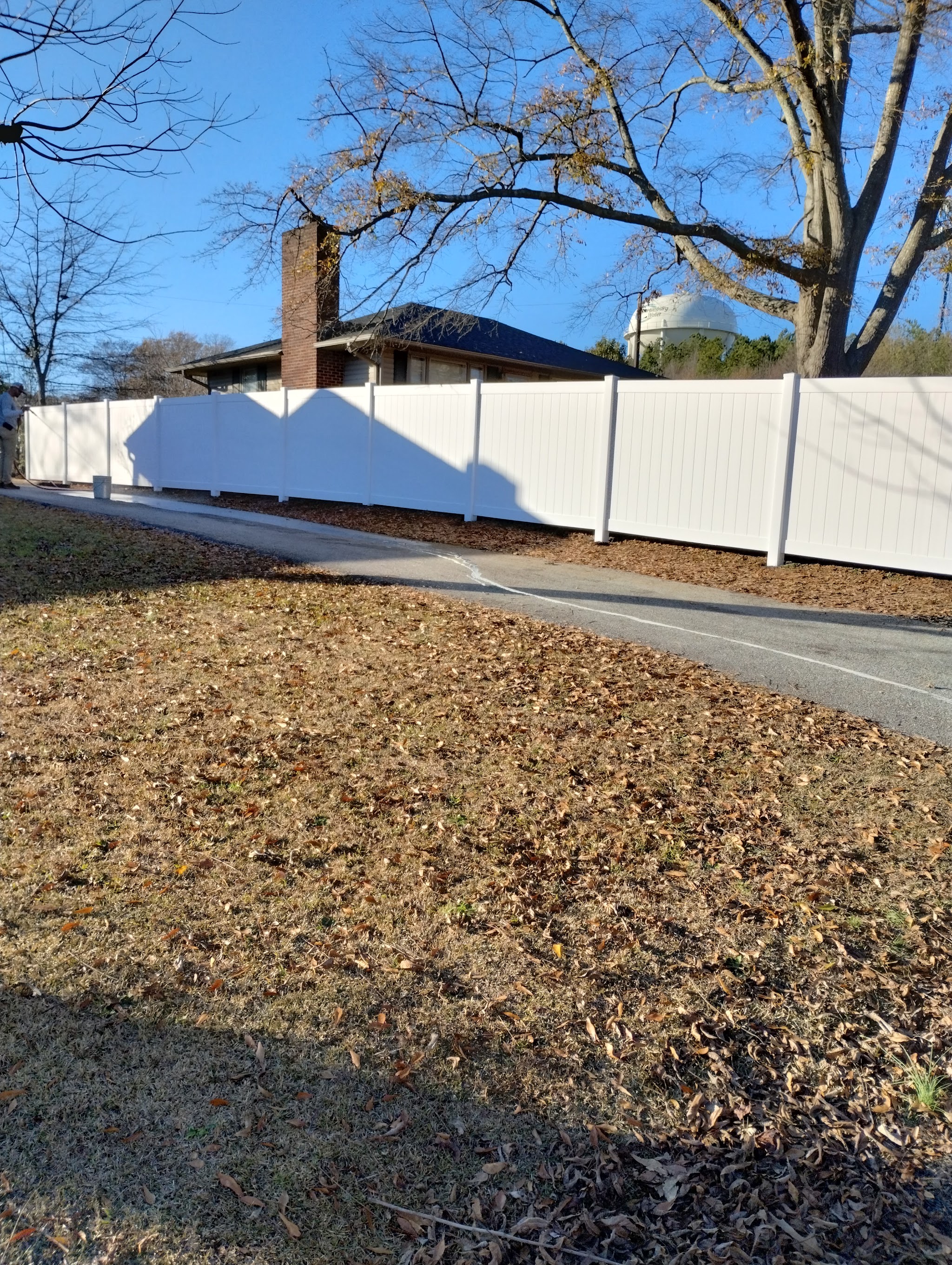 Long run of white vinyl privacy fence along a driveway